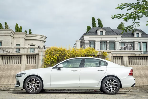 White saloon car parked outside a house.