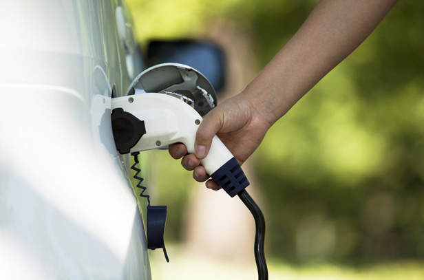 man charging electric car at home
