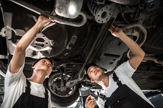 two car technicians working on the suspension during an MOT