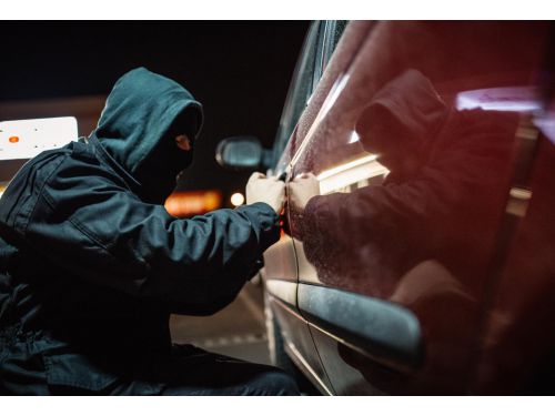 man in a hoodie stealing a car at night