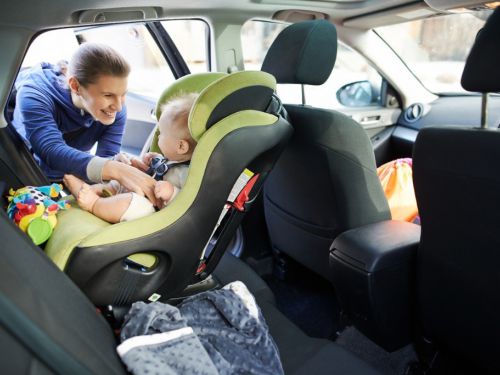 Mum strapping her baby into the car seat of a leased car