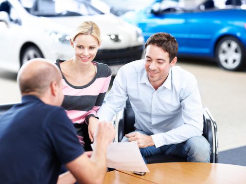 man and woman signing a document to lease their next car